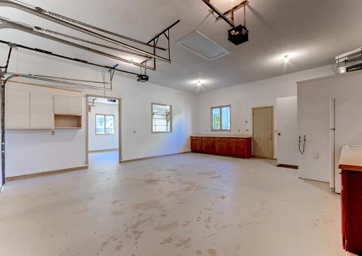 Heated garage with cabinetry, lower level basement access, and 1/4 bathroom.