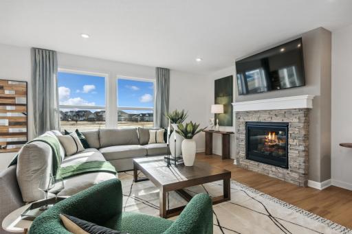 (Photo of decorated model, actual home's finishes will vary) The spacious living room seamlessly connects the kitchen area, perfect for entertaining. It also features many large windows providing warm natural light.