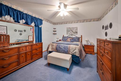 Spacious primary bedroom. Large windows are tucked behind the dresser and window treatments.