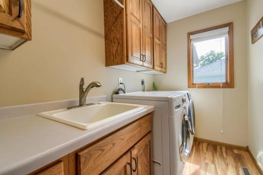 Functional laundry room with utility sink, upper cabinetry, and additional storage space. Also featuring laundry shute from primary bath.
