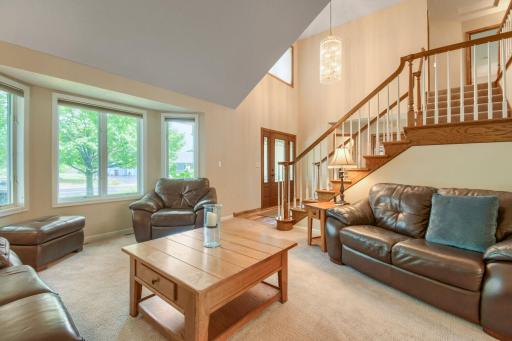 Bright, open living room featuring soaring ceilings, large windows, and an impressive staircase.