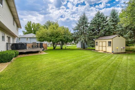 Expansive backyard with mature trees, a well-maintained lawn, deck, patio, and plenty of outdoor space.