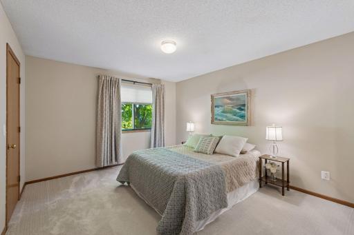 A restful primary bedroom with fresh paint, new carpet and a leafy view, plus an exceptionally spacious walk-in closet with new shelving.
