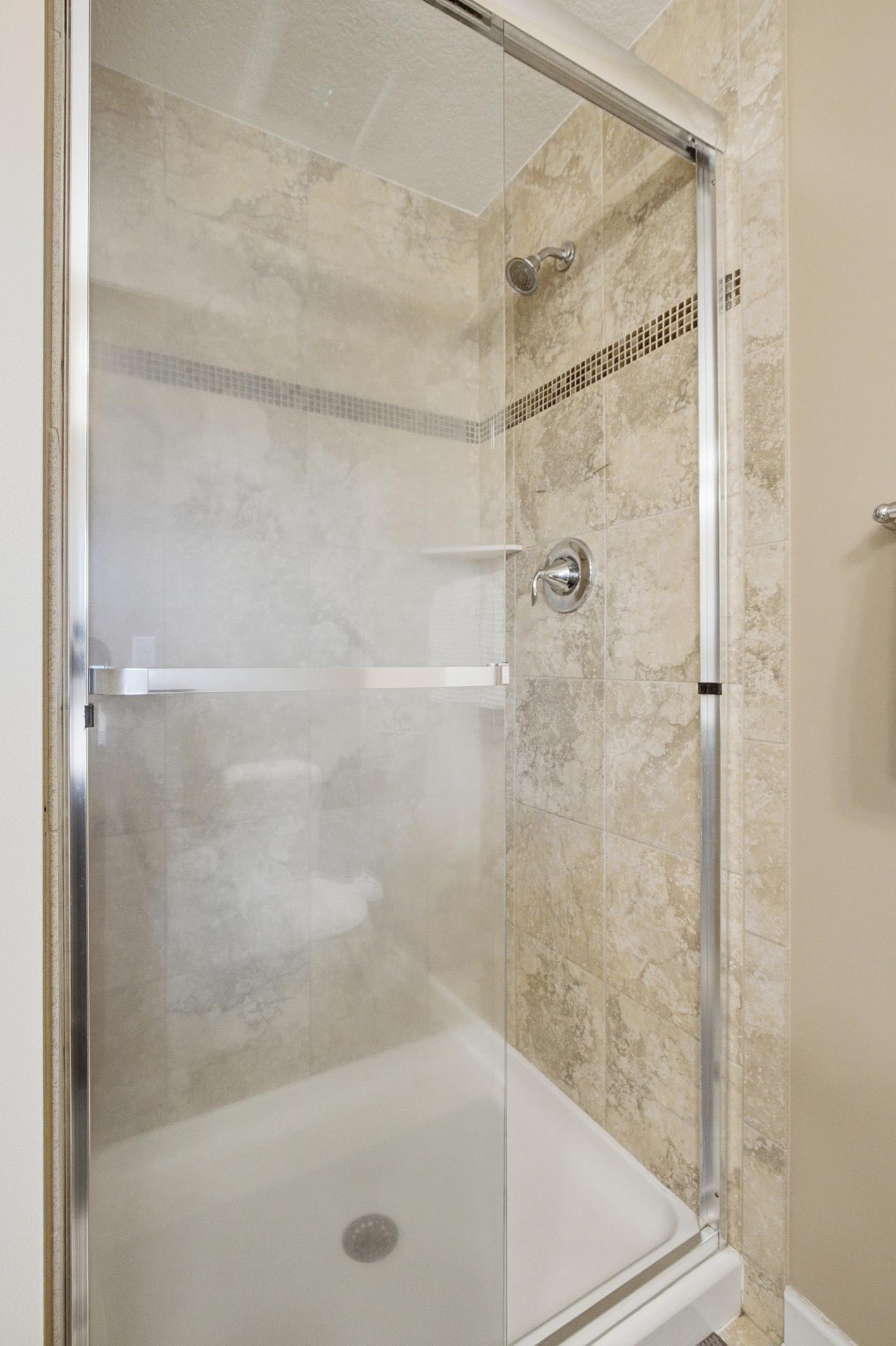 Primary bathroom ceramic tiled step in shower.