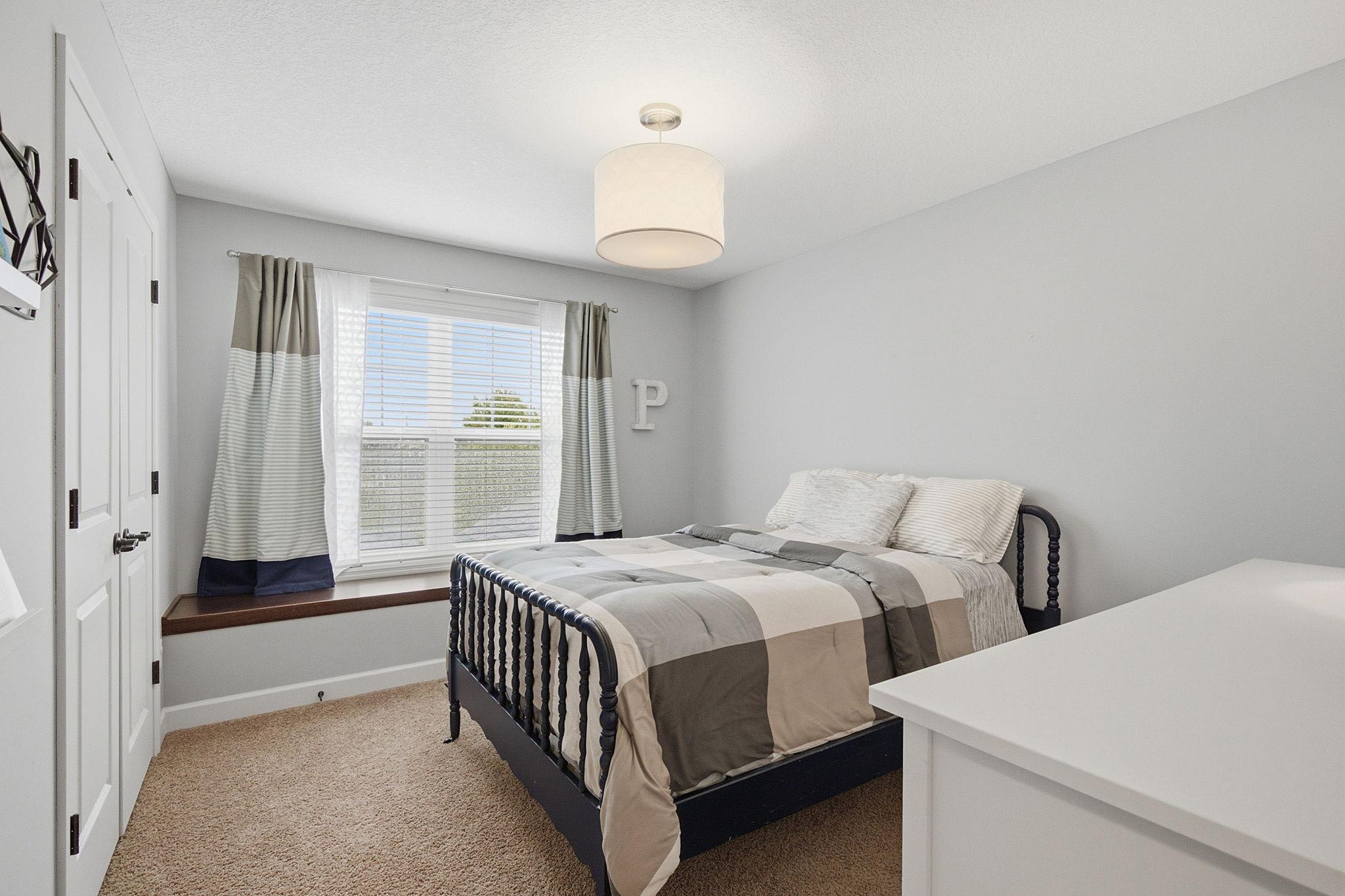 Upper-level bedroom with a sunny window, cozy window seat, neutral décor, and plenty of room for comfortable furnishings.