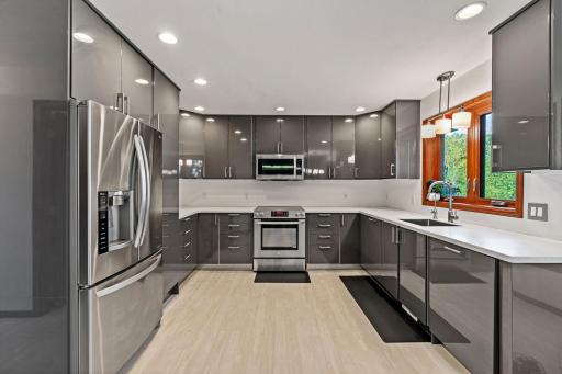 The kitchen features gray IKEA cabinetry, resin countertops, a built-in glass hutch, and stainless-steel appliances.