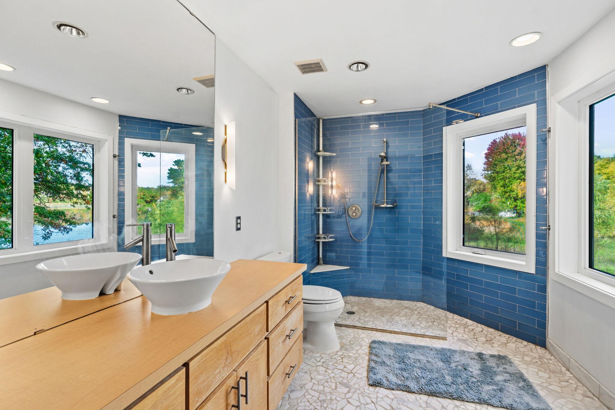 The spacious primary suite showcases vaulted ceilings, a 3/4 en-suite bath with glass incased shower, a walk-in closet and beautiful views of the water from EVERY window.