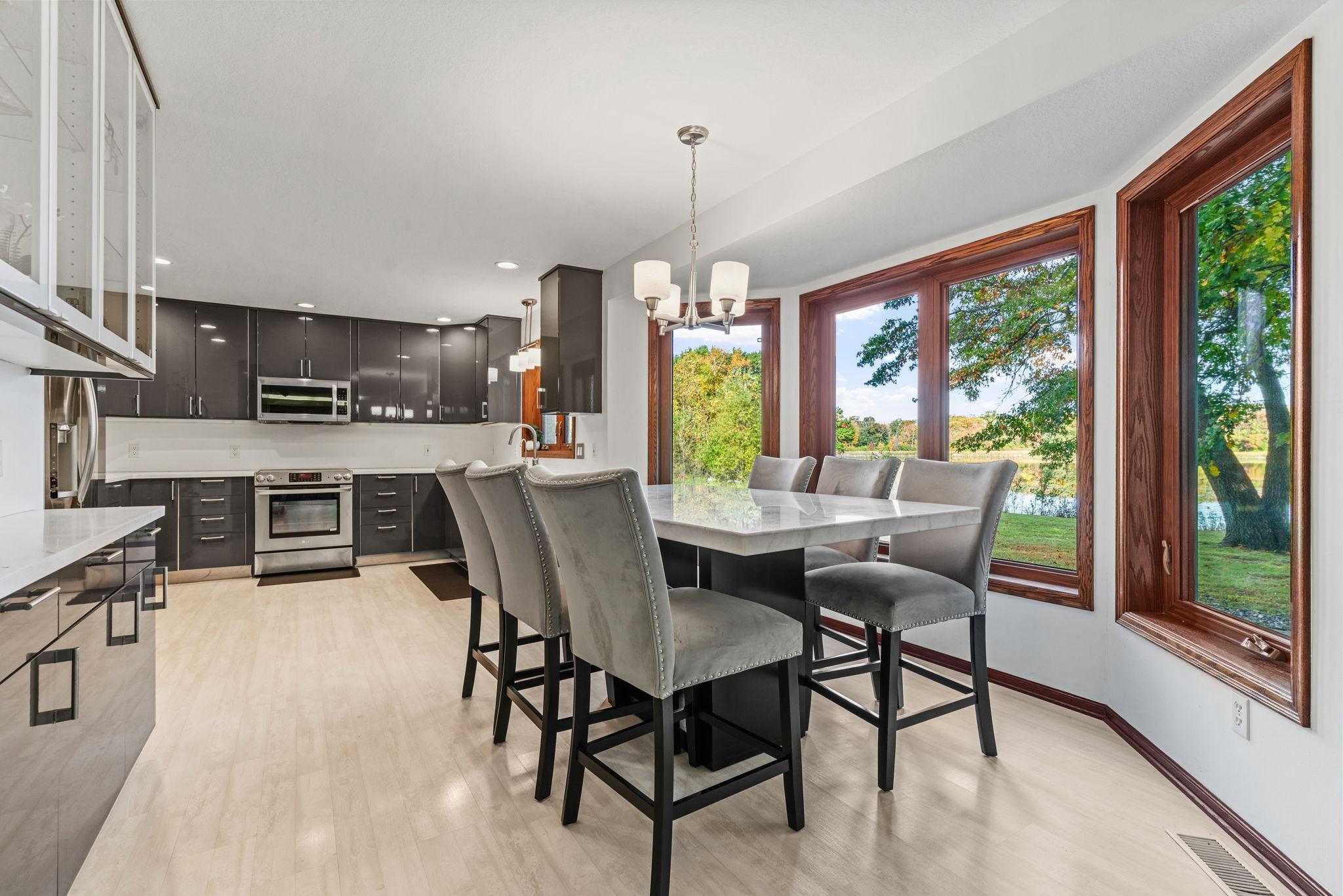 The kitchen features gray IKEA cabinetry, resin countertops, a built-in glass hutch, and stainless-steel appliances.