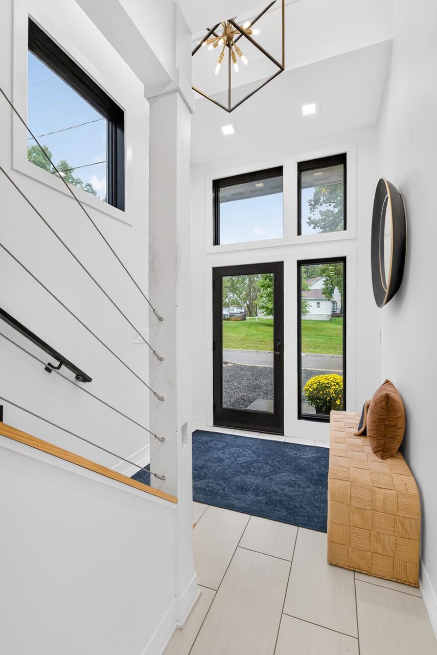 Alternate view of the two-story entry featuring large windows, glass front door and cable stair railing.