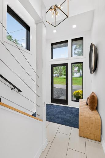 Alternate view of the two-story entry featuring large windows, glass front door and cable stair railing.