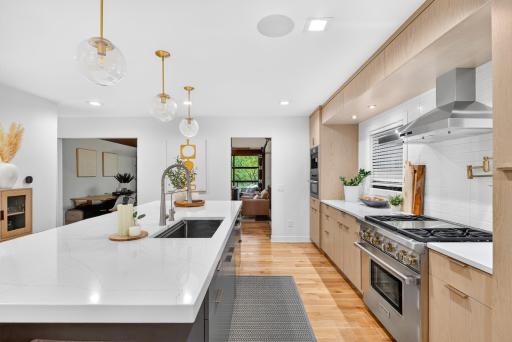Remodeled kitchen with solid white oak hardwood floors, oversized center island, quartz countertops and abundant cabinetry.