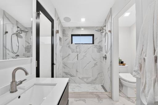 Large walk-in shower with floor-to-ceiling tile, frameless glass enclosure, built-in niche and window for natural light.