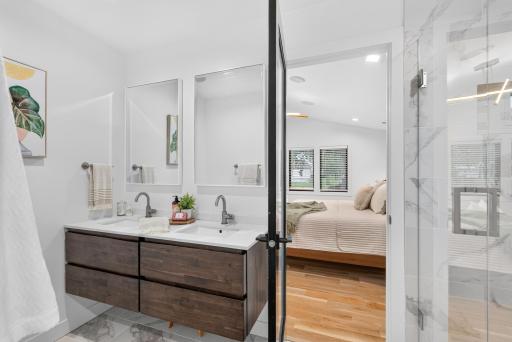 Updated primary bath features a floating double vanity, dual sinks, tiled flooring and glass-enclosed shower.