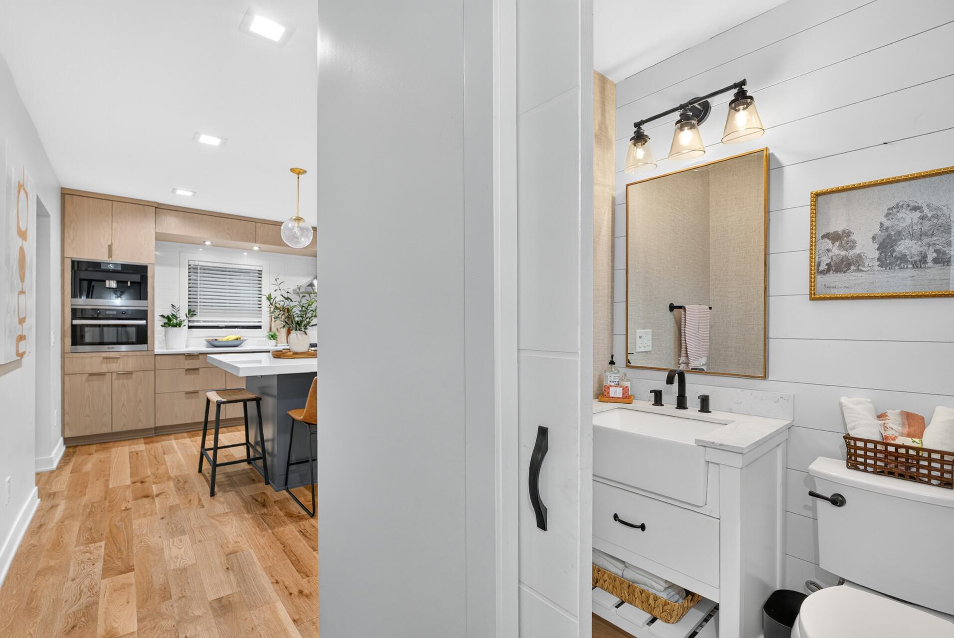 Main-level powder room features shiplap walls, modern vanity, quartz-style countertop and black fixtures.