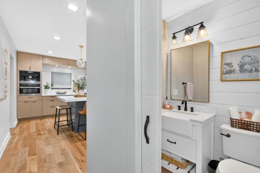 Main-level powder room features shiplap walls, modern vanity, quartz-style countertop and black fixtures.