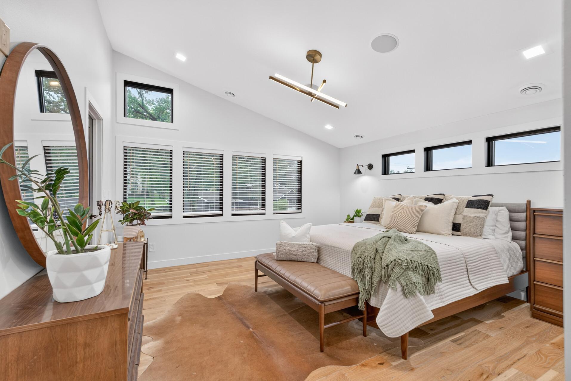 Additional view of the primary bedroom showcasing the vaulted ceiling, abundant natural light and black-trimmed windows.