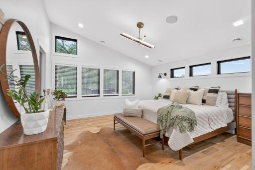 Additional view of the primary bedroom showcasing the vaulted ceiling, abundant natural light and black-trimmed windows.