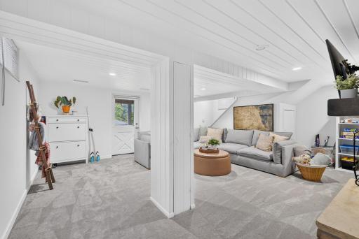 Another view of the lower-level family room highlighting the walkout access, comfortable living space, and bright, finished interior.