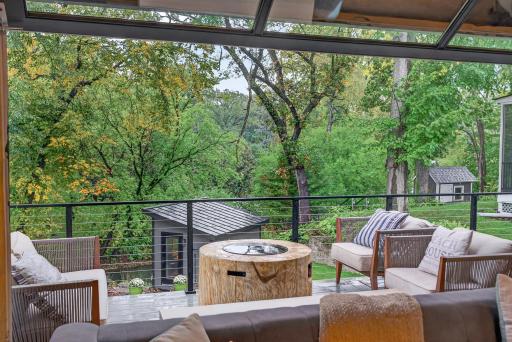 Glass garage door opens the great room to the elevated deck, creating a seamless indoor/outdoor living space with wooded backyard and channel views.