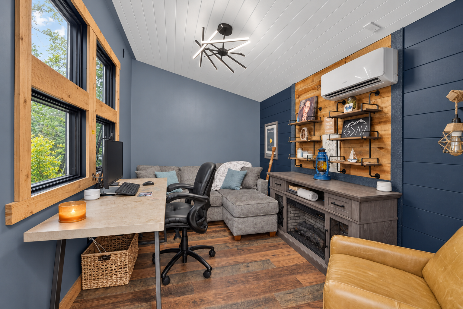 Interior of lakeside studio, currently used as a home office, featuring large windows overlooking the channel, vaulted ceiling, and a mini-split for heating and cooling.