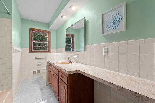 The main-level full bath offers a spacious vanity with generous counter space and convenient storage