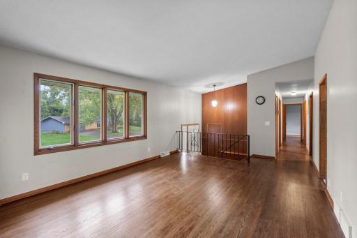 Step inside to a bright and spacious living room featuring beautiful hardwood floors and a wall of windows overlooking the yard