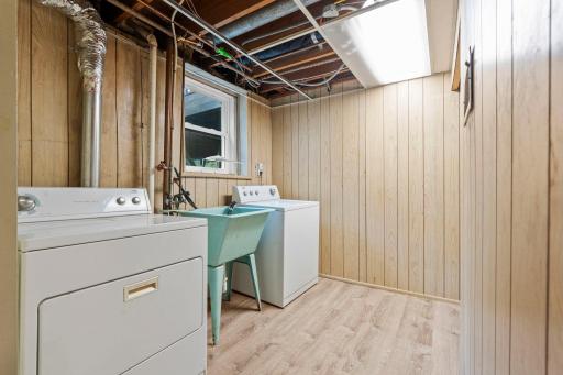Dedicated lower-level laundry space with utility sink and room for additional storage