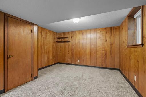 Warm wood-paneled walls add character to the lower level, with an open area ready to personalize for hobbies, recreation, or additional living space