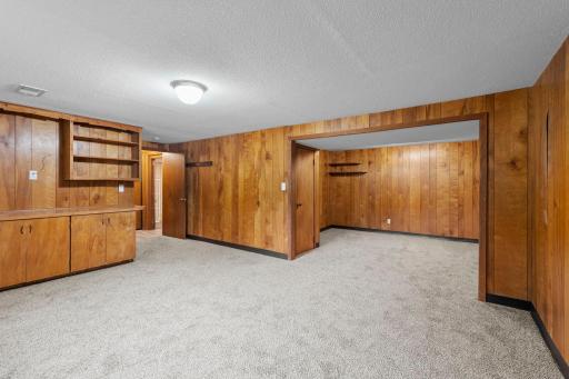Warm wood paneling gives the expansive lower-level family room plenty of character, with room to create multiple seating or activity areas