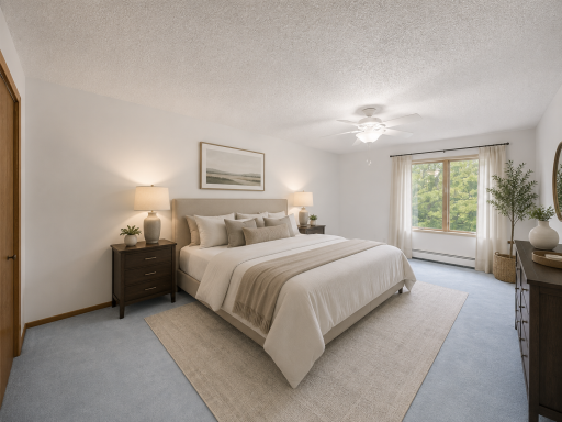 The spacious primary suite features soft carpeting, a ceiling fan, a large window with lush greenery views, and an oversized closet.