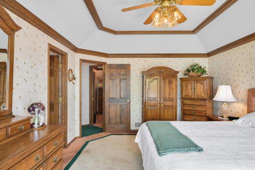 The spacious primary suite features a tray ceiling, warm woodwork and a private lakeside setting.