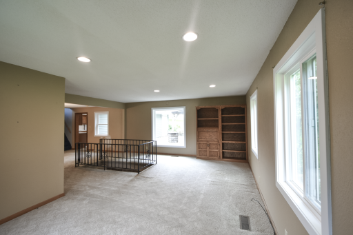 Living room area with solid wood built in shelves and large windows looking out to the backyard area.