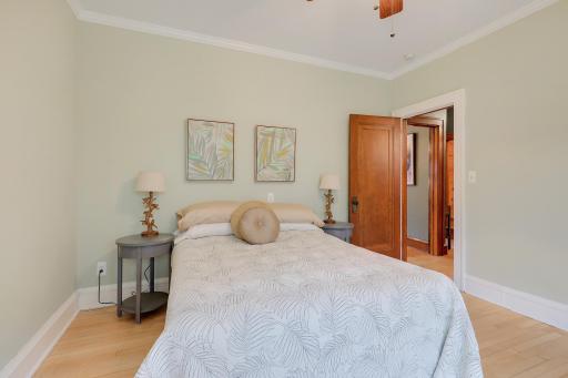 Inviting second bedroom featuring hardwood floors, soft neutral colors, and classic wood doors.