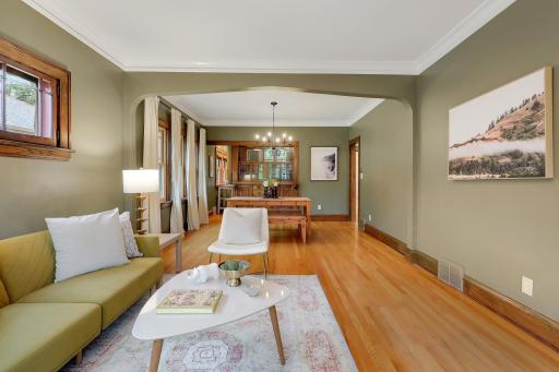 Connected living and dining spaces showcase hardwood floors, rich wood trim, and a graceful arched opening.