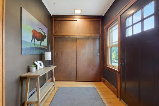 Inviting entry featuring warm woodwork, hardwood flooring, and a spacious coat closet.