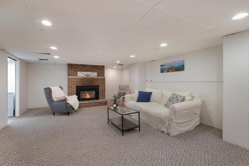 Comfortable lower-level family room with a brick fireplace and plenty of space to relax or gather.