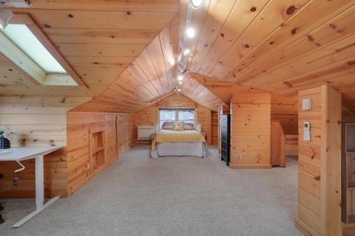 Cozy loft bedroom featuring wood-paneled walls, an angled ceiling, and built-in storage.