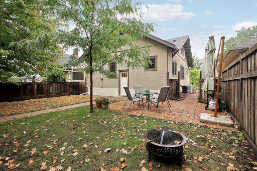 Welcoming backyard with a brick patio, mature trees, and wood fencingâan inviting setting for outdoor dining and relaxing.