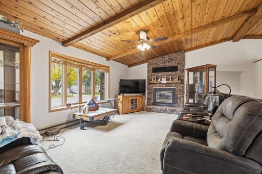 Step inside to a cozy living space featuring a warm, wood vaulted ceilings and a brick fireplace