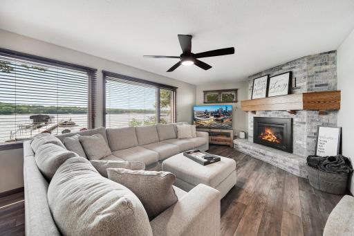 Updated interior with a cozy fireplace, newer flooring, and a great panoramic view of the lake.