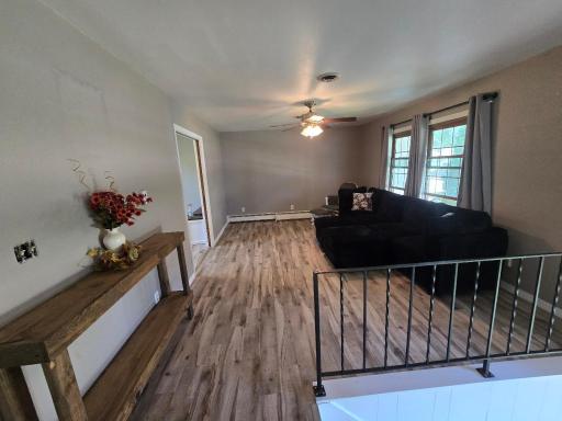 Living room features ceiling fan & west facing windows.