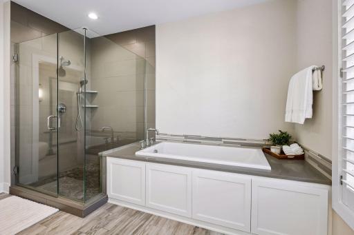 Spa-like primary bath features a separate soaking tub, double sinks, walk-in shower, and private toilet area.