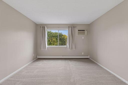 Main bedroom with beautiful painting, carpet, and drapes.