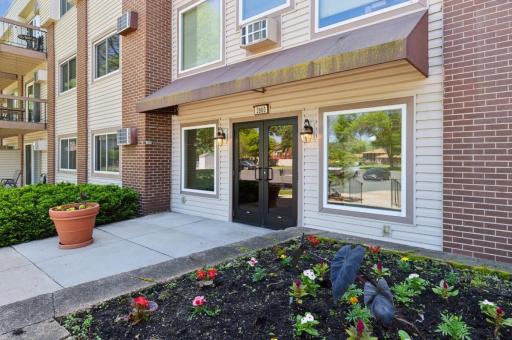 Natural plantings, bushes, flowers and trees surround condo building.