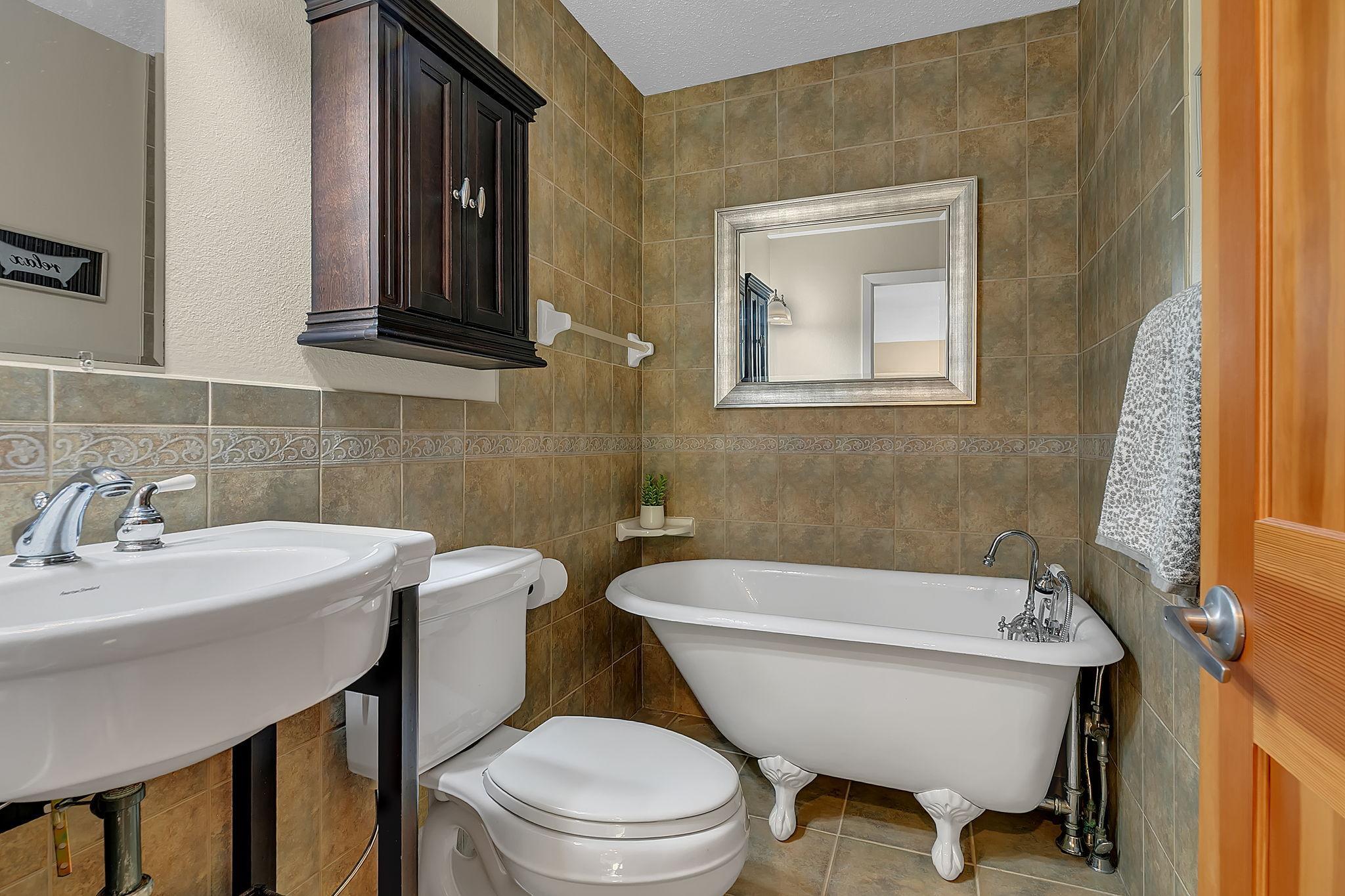 Charming main-level 3/4 bath with a classic clawfoot tub—perfect for a relaxing soak after a day on the links or the lake