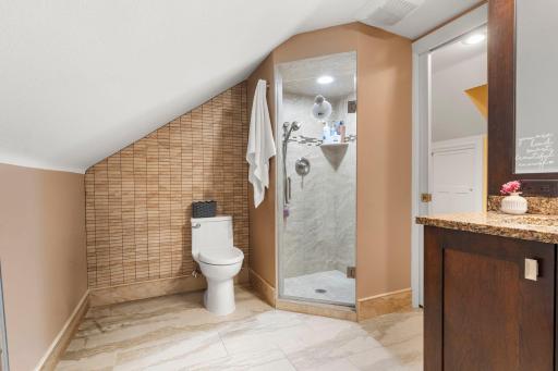 The upper-level bathroom also features a walk-in shower with a stunning tile surround.