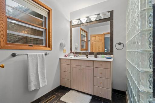 Featuring a single vanity with plenty of storage, while backyard views bring natural light into the space.