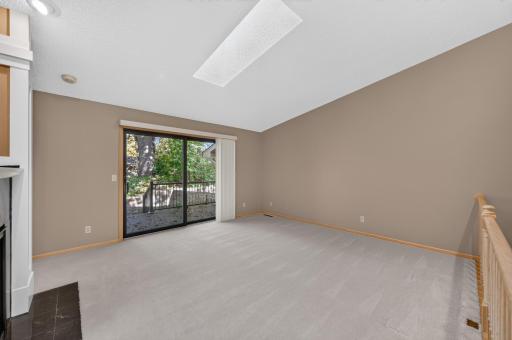 The large living room is highlighted by vaulted ceiling, skylight, and lovely gas fireplace.
