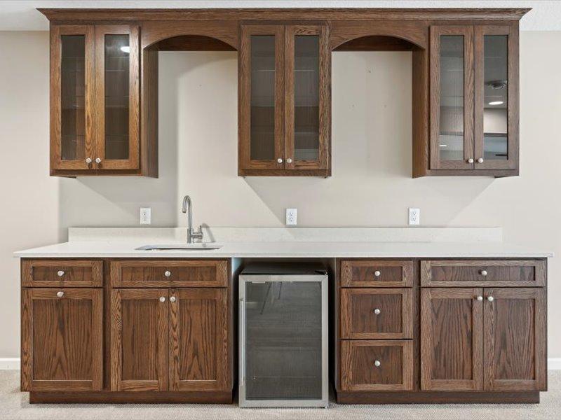 Full wet bar with nice cabinetry, solid surface counter, and wine frig