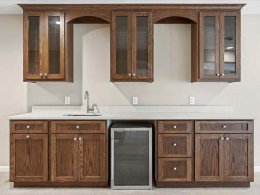 Full wet bar with nice cabinetry, solid surface counter, and wine frig